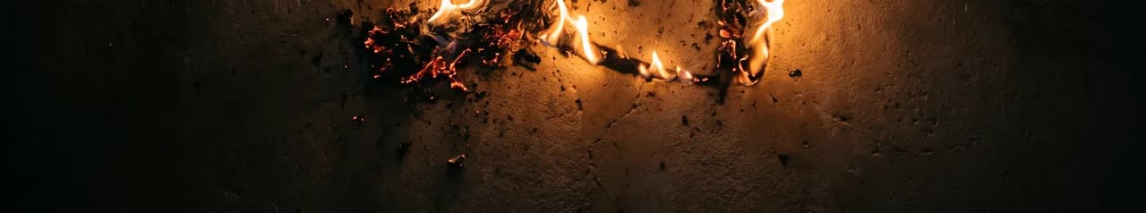The Umber ribbon-knot mark burning into a cracked plaster wall at night.