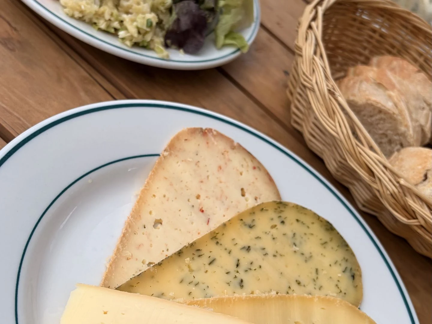 Product photograph: two cut French cheeses on a plate with a bread basket behind.