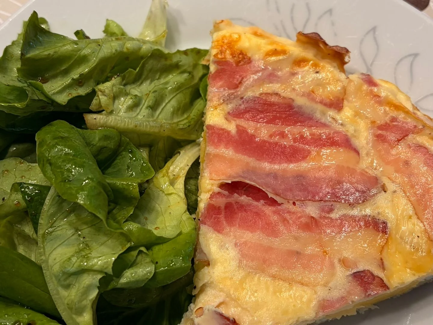 Recipe photograph: a slice of quiche lorraine served with dressed green salad.